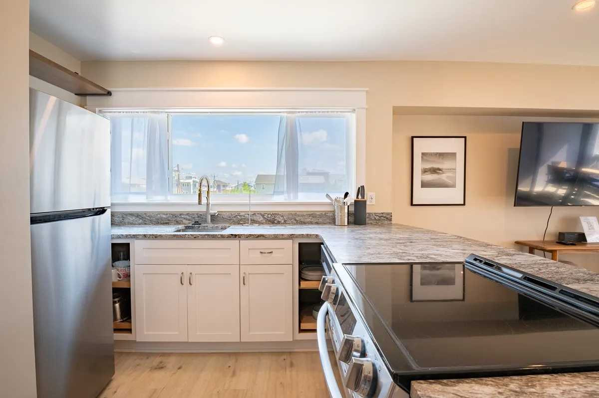 This image highlights an inviting kitchen with a countertop, sink, stove, window with a view, and a TV. The space feels bright and welcoming, suggesting a spot where guests can gather, cook meals together, and enjoy casual breakfasts before heading out to explore.